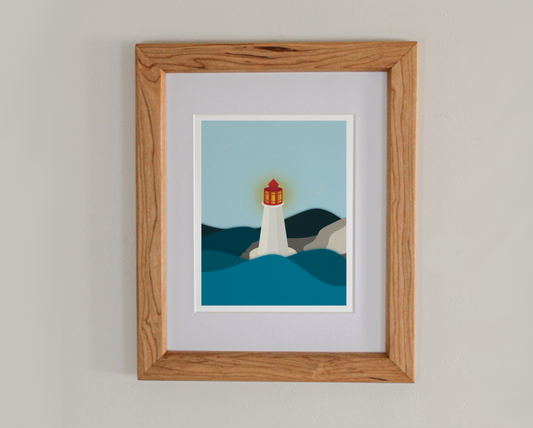 An art print of a lit lighthouse on a rocky shore surrounded by sea in a cherry hardwood frame